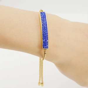 Detail of adjustable 18K gold bracelet with blue pave crystals on woman's wrist