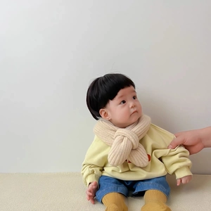 Detailed view of baby knitted cross scarf in beige soft wool with warm autumn winter outfit