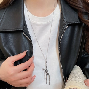 Detail of silver skull pendant necklace with movable joints worn on black leather jacket