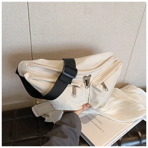 Detail of off-white nylon crossbody bag showing multiple pockets and black wide strap