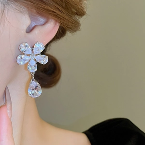 Close-up of sparkling floral zircon drop earrings worn by a model for a luxury look