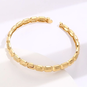 Gold plated geometric cuff bracelet with textured bamboo design on a display stand