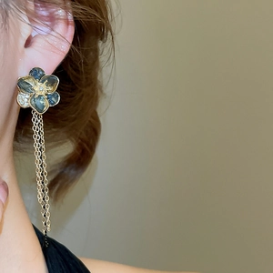 Detail of flower tassel earrings with grey crystals and gold chains worn on model