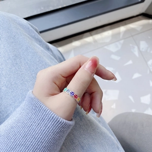 Detail of 925 silver open ring featuring colorful enamel smiley face charms on a finger