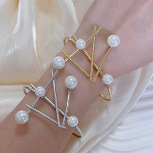 Modern irregular geometric metal bangles featuring white pearls in gold and silver finish