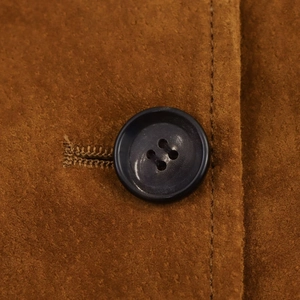 Vue macro du tissu en daim marron avec des coutures fines et le détail d'un bouton noir