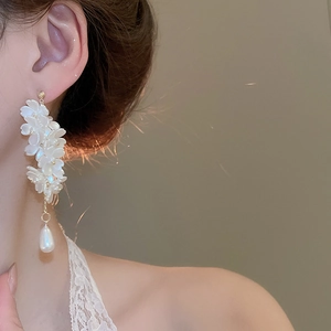 Macro detail of elegant floral tassel earrings with waterdrop pearls and golden accents