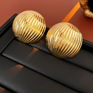 Detail view of golden striped dome stud earrings resting on a black leather jewelry box