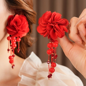 Gros plan détaillé de boucles d'oreilles fleurs en tissu rouge avec glands en perles rouges