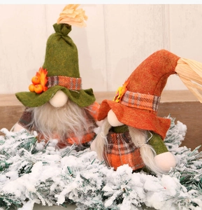 Detail of two harvest gnomes with maple leaf hats and white beards on pine branches