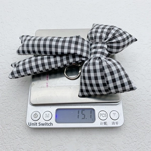 Detail shot showing the lightweight fabric bow charm on a scale weighing 15.1 grams