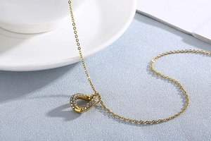 Close-up of golden irregular necklace with rhinestone details on textured background