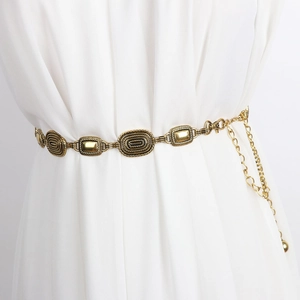 Détail d'une ceinture chaîne en métal doré vintage avec maillons texturés
