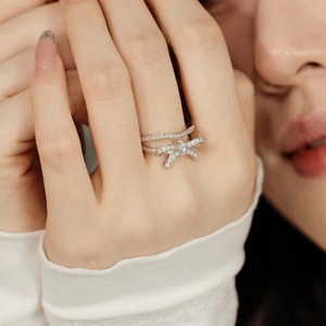Close-up of stacked S925 silver rings featuring bowknot and V-shaped crystal designs