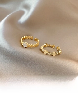 Detail of vintage gold-plated rings with opalescent stones on luxury silk fabric