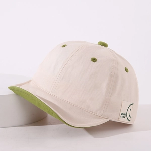 Detail of baby soft brim baseball cap featuring Good Luck label and smiley face design