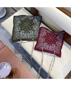 Detail of paisley print tote bags with colorful beaded cords on a soft sofa