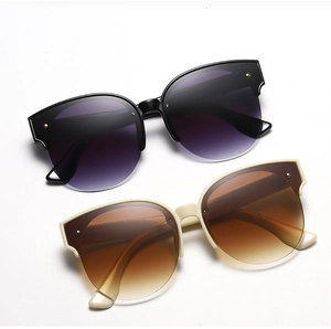 Detail of round cat-eye sunglasses with black and beige frames and gradient lenses