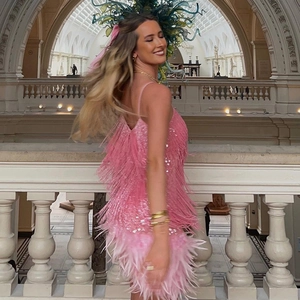 Détail d'une robe à paillettes rose avec franges, plumes et pampilles sur un mannequin