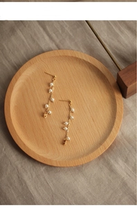 Detailed macro view of long tassel earrings with natural white pearls on a gold chain
