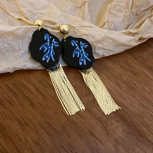 Detailed view of long gold tassels and black floral pattern on elegant oriental earrings