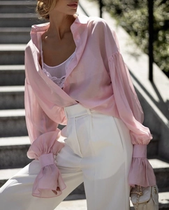 Detail of pink sheer chiffon shirt with large cuffs and white lace top on stone steps