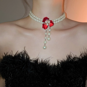 Detail of elegant double-layer pearl necklace with red floral rhinestone pendant on model