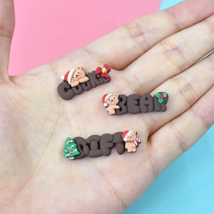 Close-up of three Christmas bear resin charms for DIY crafts held in a person's hand