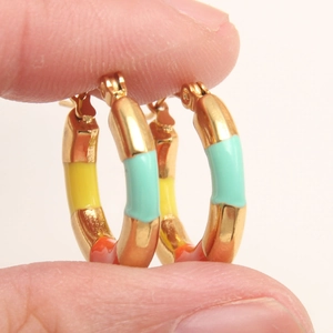 Detail of gold-plated hoop earrings featuring colorful enamel bamboo segments and click-top closure