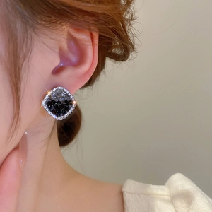 Elegant square stud earrings with black crystal and small diamonds worn by a model