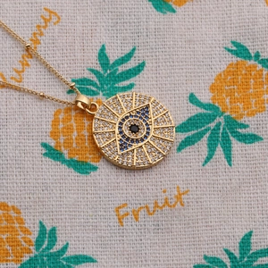 Close-up of gold-plated evil eye necklace with blue zircon and clear stones