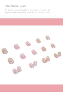 Detail of pink press-on nails featuring gold foil accents and 3D white bow designs