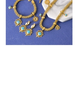 Detailed set of gold titanium clover jewelry with turquoise stones on blue marble