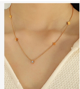 Close-up of a gold star necklace with small flower charms and a round zircon on a model