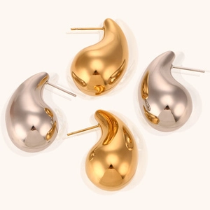 Vista macro di orecchini a goccia minimalisti in metallo lucido oro e argento