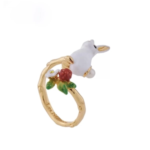 Macro view of white enamel rabbit and red berry detail on branch-style ring