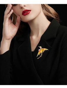 Detailed close-up of a phoenix brooch with orange rhinestones on a black suit jacket