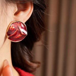 Close-up of vintage red drip oil round earrings with irregular golden frames for women