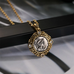 Détail macro du pendentif pièce vintage avec texture dorée et portrait argenté embossé