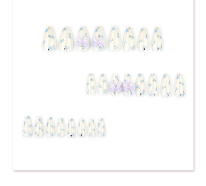 Detailed view of long almond press-on nails with blue floral patterns and 3D purple bows
