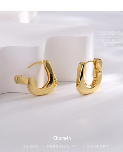Detailed close-up of golden asymmetric geometric earrings with minimalist brushed finish