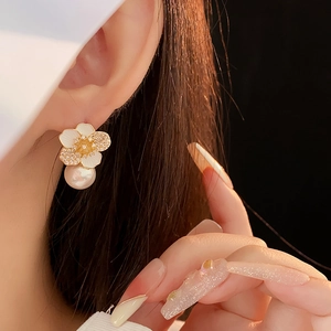 Macro shot of a floral pearl earring with pavé zircon petals worn on the ear