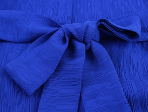 Detail einer königsblauen Schleife mit Plissee-Struktur für ein elegantes Damenkleid