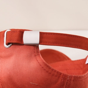 Detail of red cotton baseball cap with adjustable silver metal buckle and fine stitching