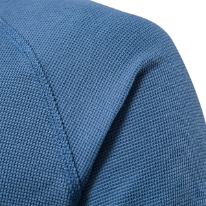 Gros plan sur la maille gaufrée bleu-gris, texture alvéolée et coutures d'épaule précises