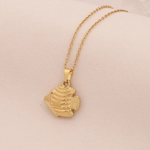 Goldene Edelstahlkette mit Fischanhänger auf weichem Stoffhintergrund präsentiert