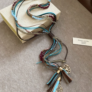 Detail of bohemian tiered necklace with colorful beads, leather tassels and gold pendants