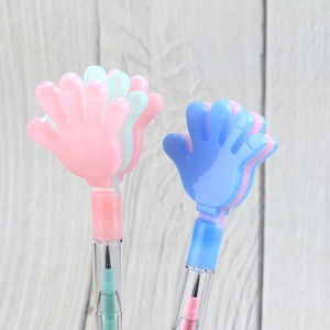 Close-up of colorful palm-shaped creative pens with transparent barrels on wood background