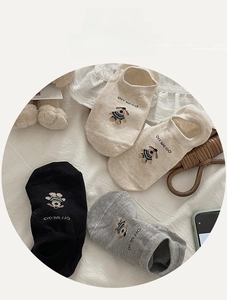 Detailed view of three cotton no-show socks with cute dog embroidery in beige, black, and grey