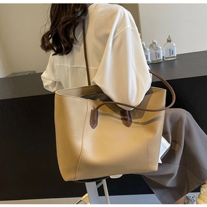 Detailed view of khaki large tote bag featuring slim dark brown straps and soft leather texture